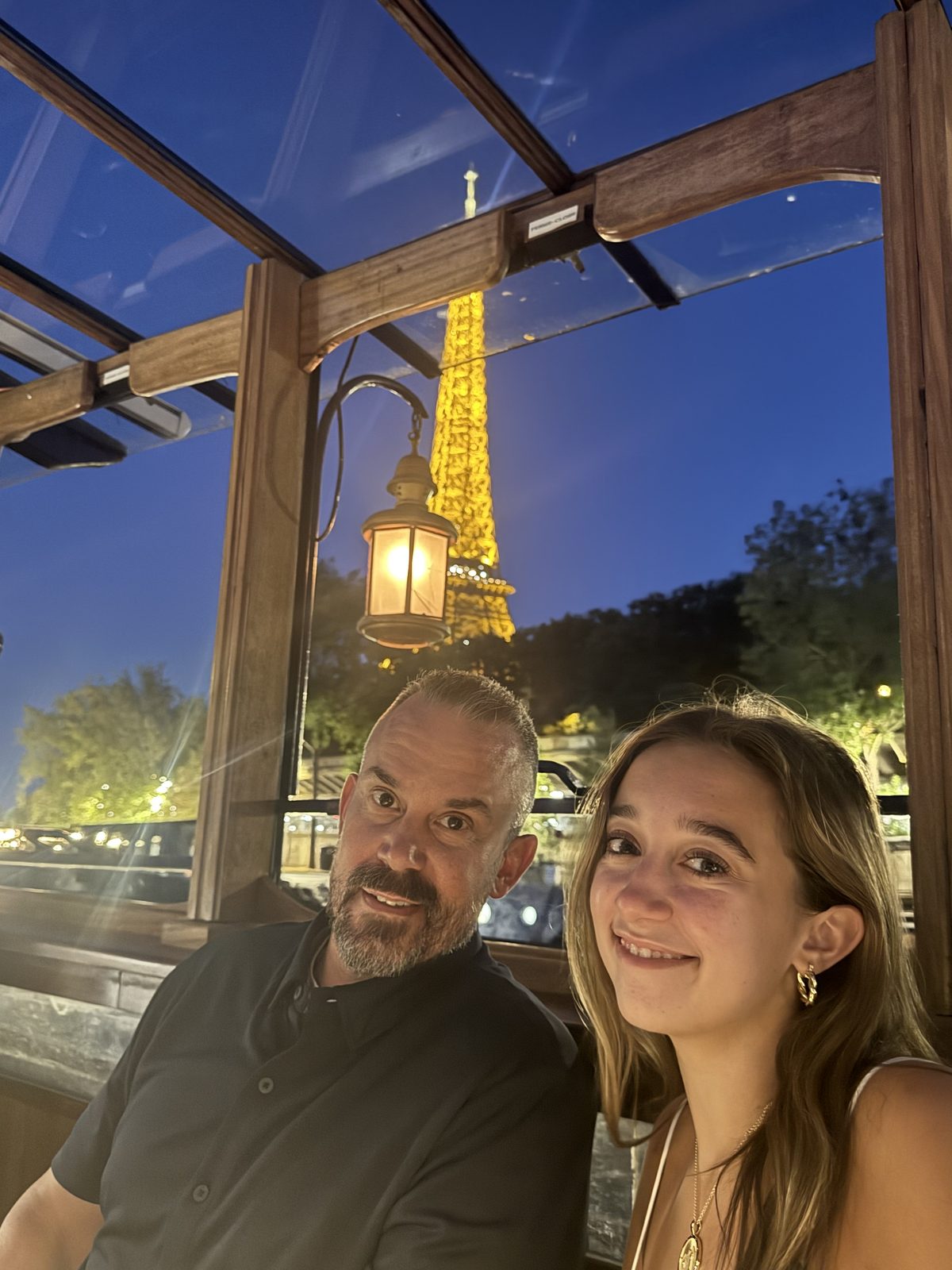 Evening dinner cruise on the Seine with the Eiffel Tower lit gold through the window.